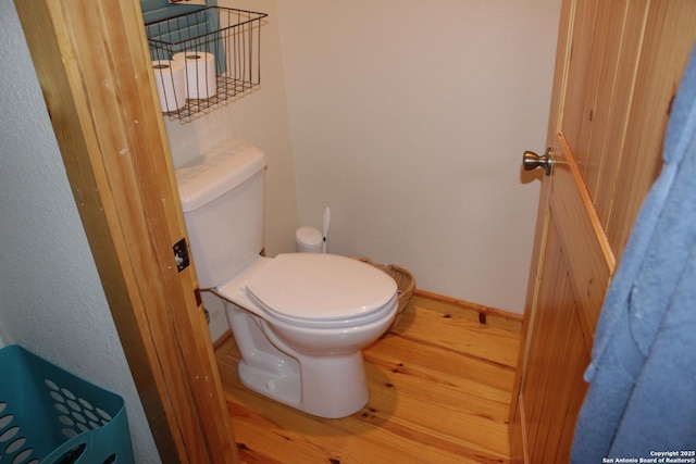 bathroom with toilet, baseboards, and wood finished floors