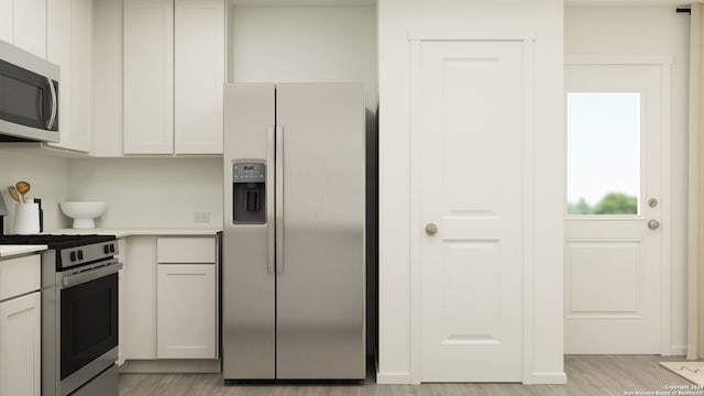 kitchen with light countertops, appliances with stainless steel finishes, white cabinets, and light wood-style floors