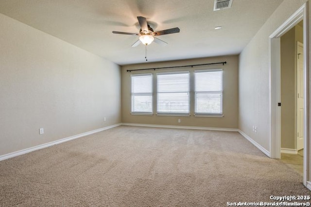 empty room with baseboards, ceiling fan, light colored carpet, and visible vents