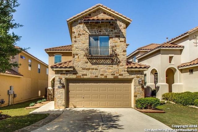 mediterranean / spanish-style home with a garage, stone siding, stucco siding, a tiled roof, and driveway