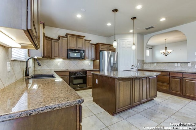 kitchen with light stone counters, a sink, arched walkways, a wealth of natural light, and black appliances