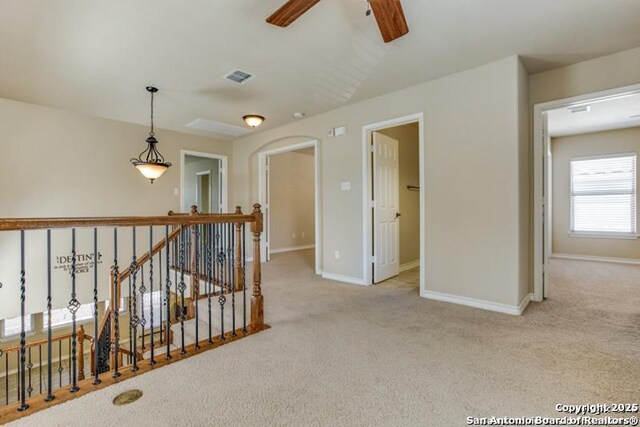 hall with baseboards, visible vents, carpet flooring, and an upstairs landing