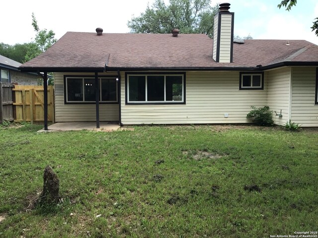 back of property featuring fence, a patio, a chimney, and a lawn