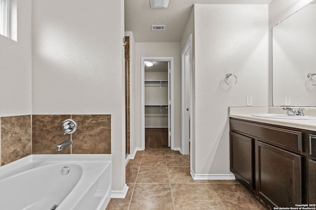 7111 Phoebe Vw, San Antonio, TX 78252 - full bathroom featuring a walk in closet, a bath, baseboards, vanity, and tile patterned floors