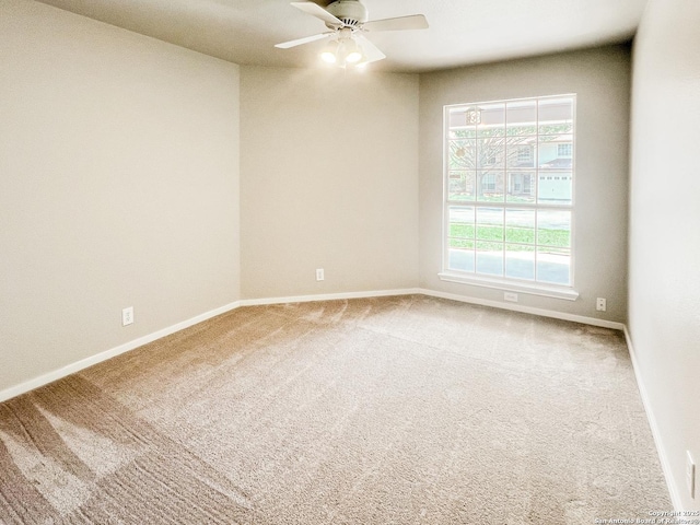 carpeted empty room featuring baseboards and ceiling fan