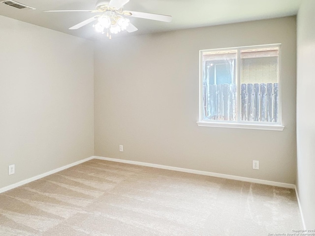 spare room featuring visible vents, a ceiling fan, baseboards, and light carpet