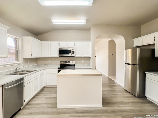 kitchen with stainless steel appliances, arched walkways, white cabinetry, and a sink