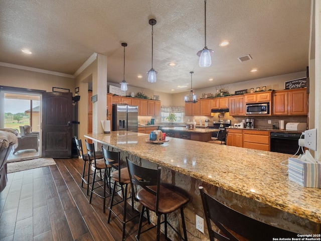 kitchen featuring dark wood-style flooring, stainless steel appliances, a textured ceiling, and plenty of natural light