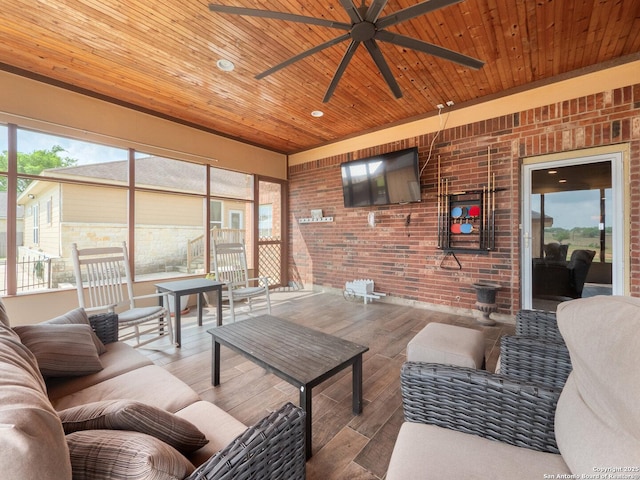 living area with a ceiling fan, wood finished floors, brick wall, and wooden ceiling