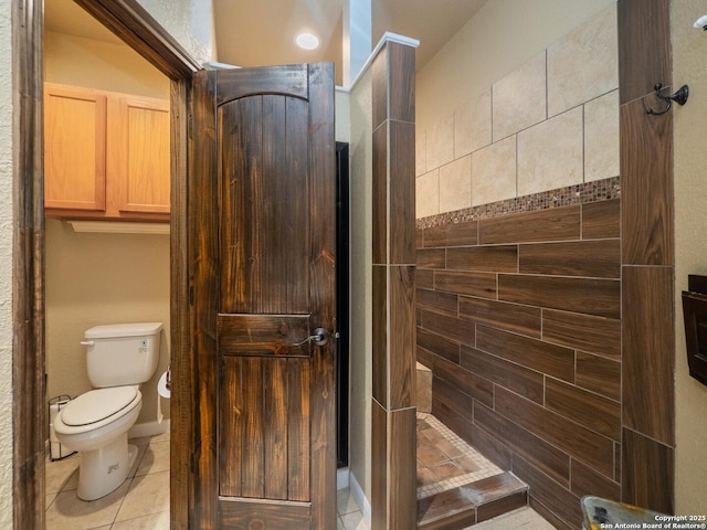 bathroom with toilet, tile patterned floors, and a tile shower