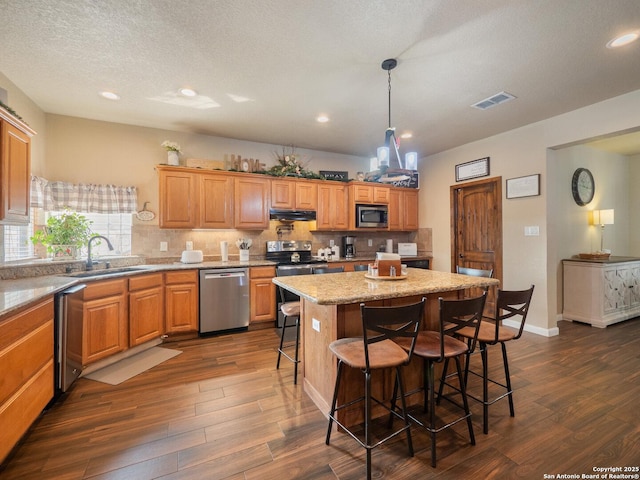 kitchen with a sink, dark wood finished floors, a breakfast bar, and stainless steel appliances