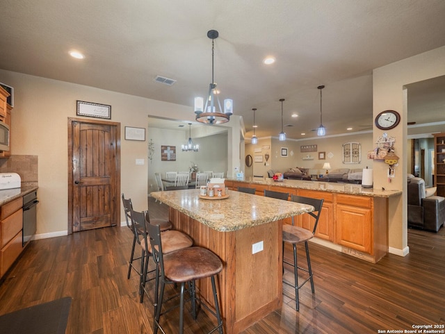 kitchen with a breakfast bar area, open floor plan, a notable chandelier, and dark wood-type flooring