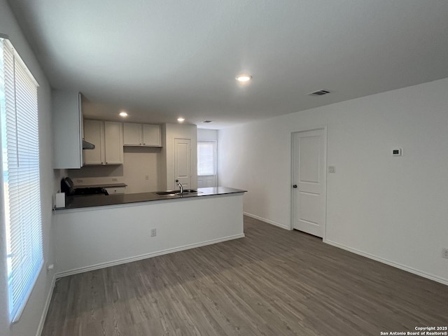8823 Astral Pl, San Antonio, TX 78252 - kitchen with visible vents, a peninsula, dark countertops, stove, and dark wood-style floors