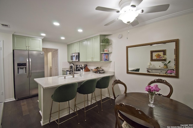 kitchen featuring ceiling fan, visible vents, a sink, green cabinetry, and stainless steel appliances