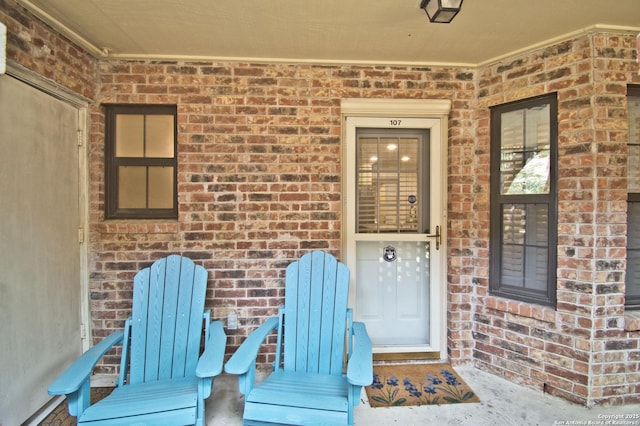view of exterior entry featuring covered porch and brick siding
