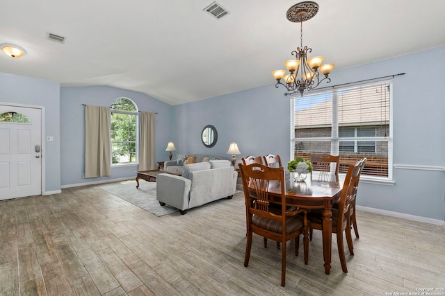 dining room with light wood-style floors, lofted ceiling, and visible vents