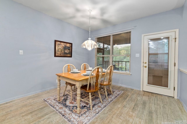 dining room featuring baseboards, light wood-style flooring, and a notable chandelier