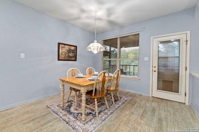 23003 Tornillo Dr, San Antonio, TX 78258 - dining room featuring baseboards, light wood-style flooring, and a notable chandelier
