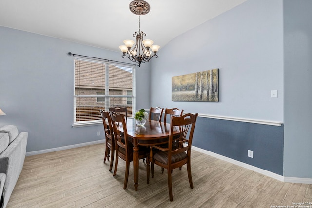 dining space with baseboards, wood finished floors, and a notable chandelier