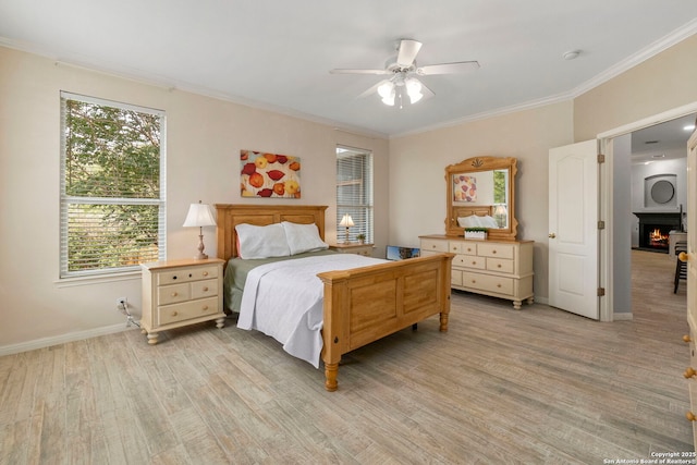 bedroom with light wood-style floors, ornamental molding, baseboards, and a lit fireplace