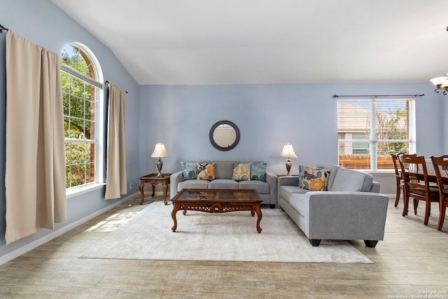 living area featuring an inviting chandelier, plenty of natural light, vaulted ceiling, and wood finished floors