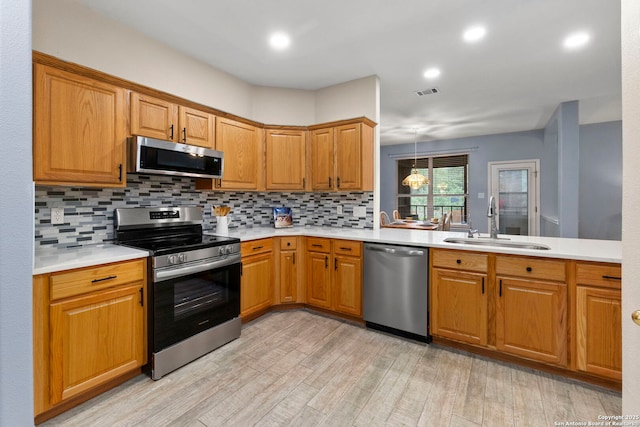 kitchen with light wood-type flooring, light countertops, a sink, appliances with stainless steel finishes, and backsplash