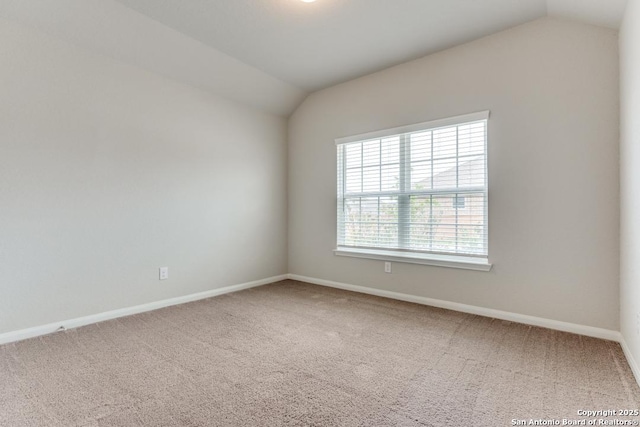 carpeted spare room with baseboards and lofted ceiling