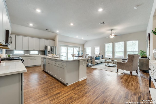 kitchen with stainless steel appliances, ceiling fan, dark wood finished floors, and open floor plan