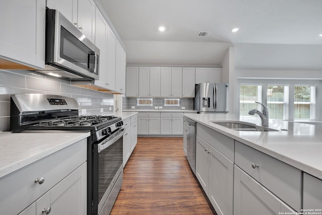 kitchen with appliances with stainless steel finishes, a sink, recessed lighting, decorative backsplash, and dark wood-style floors