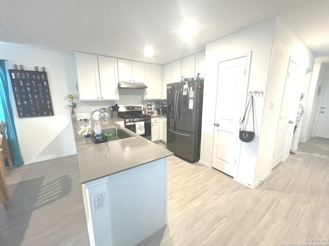 kitchen with stainless steel gas range oven, under cabinet range hood, fridge with ice dispenser, a sink, and light wood-style flooring