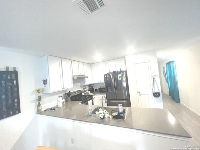 kitchen featuring visible vents, appliances with stainless steel finishes, a sink, a peninsula, and under cabinet range hood