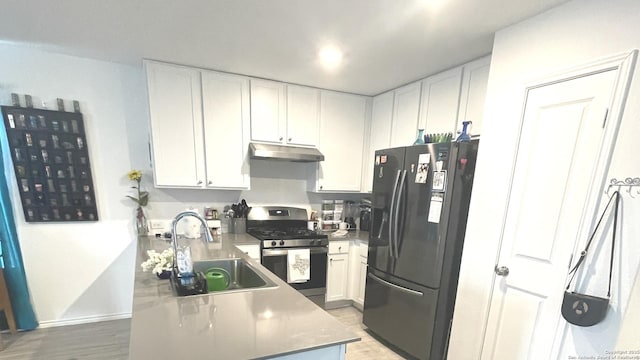 kitchen featuring refrigerator with ice dispenser, a sink, gas stove, and white cabinetry