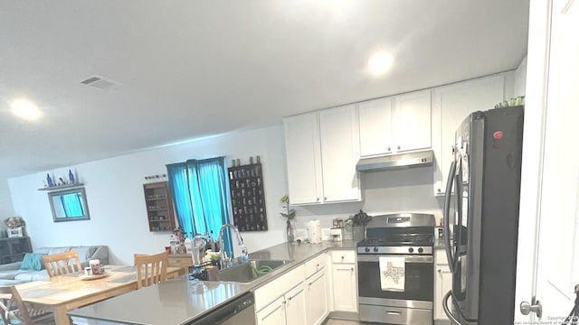 kitchen featuring a sink, stainless steel appliances, open floor plan, a peninsula, and under cabinet range hood