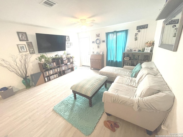 living room with a ceiling fan, wood finished floors, and visible vents