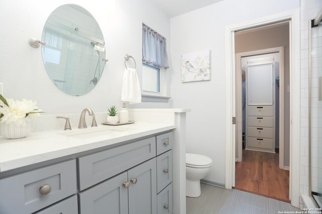 bathroom with vanity, a shower with door, baseboards, and toilet
