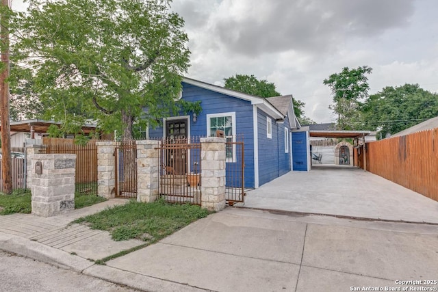 bungalow with a gate, a fenced front yard, driveway, and a carport