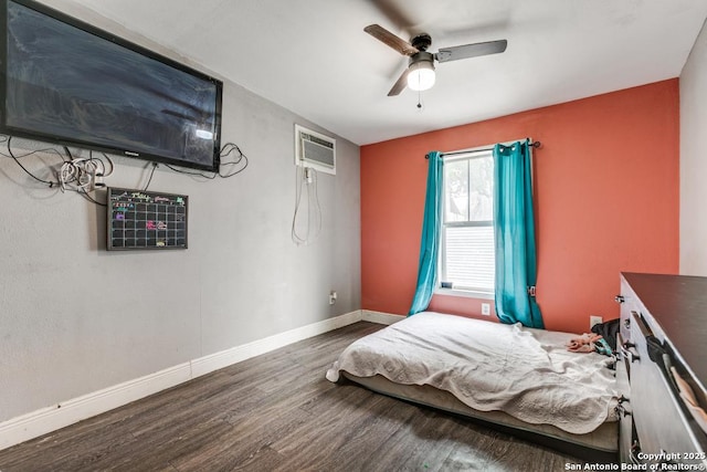 bedroom with baseboards, a ceiling fan, wood finished floors, and an AC wall unit
