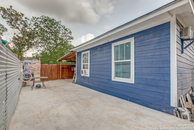 view of side of property featuring fence, a patio, and cooling unit
