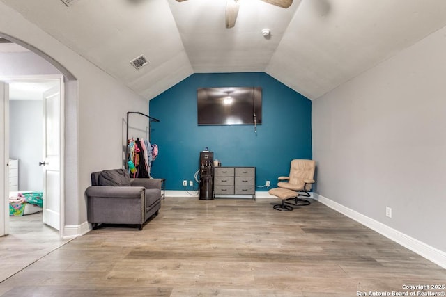living area featuring a ceiling fan, arched walkways, visible vents, and wood finished floors