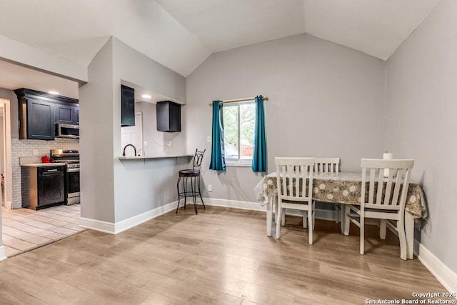 dining room featuring light wood-style floors, baseboards, and lofted ceiling