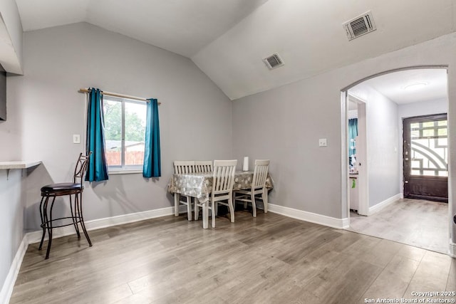 dining area featuring visible vents, arched walkways, and wood finished floors