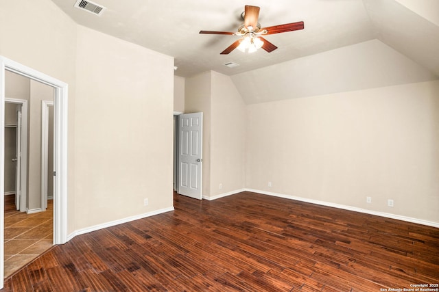 additional living space with visible vents, baseboards, dark wood-type flooring, a ceiling fan, and vaulted ceiling