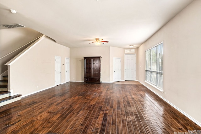 unfurnished living room with ceiling fan, baseboards, visible vents, dark wood-style floors, and stairway