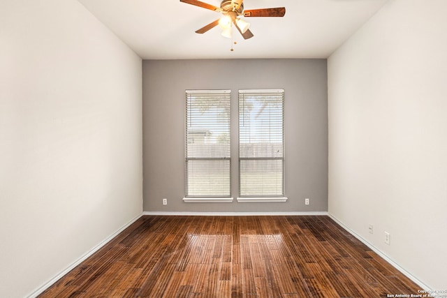 empty room with baseboards, ceiling fan, and dark wood-style floors