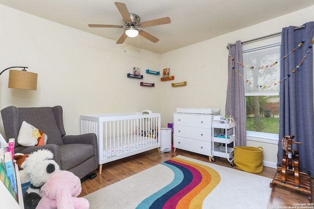 202 Beverly Dr, San Antonio, TX 78228 - bedroom with a crib, ceiling fan, baseboards, and wood finished floors