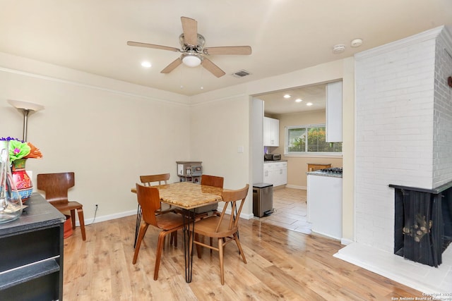202 Beverly Dr, San Antonio, TX 78228 - dining room featuring a brick fireplace, a ceiling fan, baseboards, light wood-type flooring, and visible vents