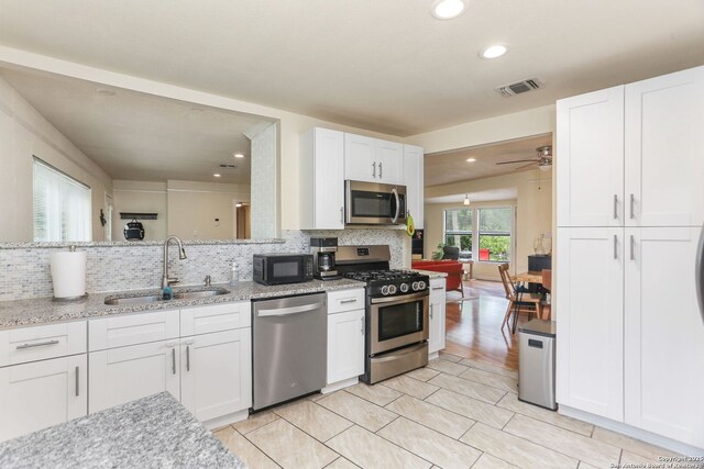 202 Beverly Dr, San Antonio, TX 78228 - kitchen featuring a sink, white cabinets, backsplash, and stainless steel appliances