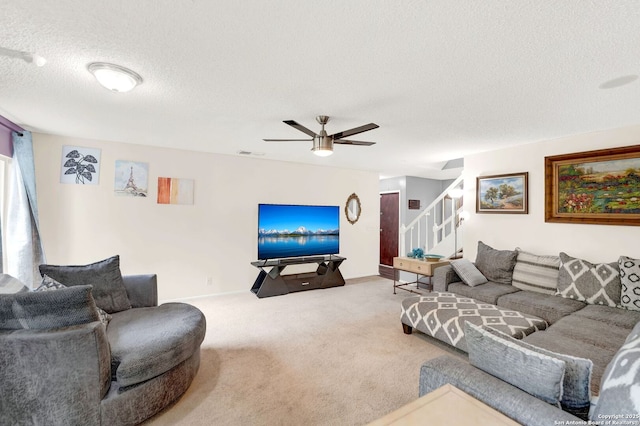 living area with carpet floors, a textured ceiling, stairs, a ceiling fan, and visible vents