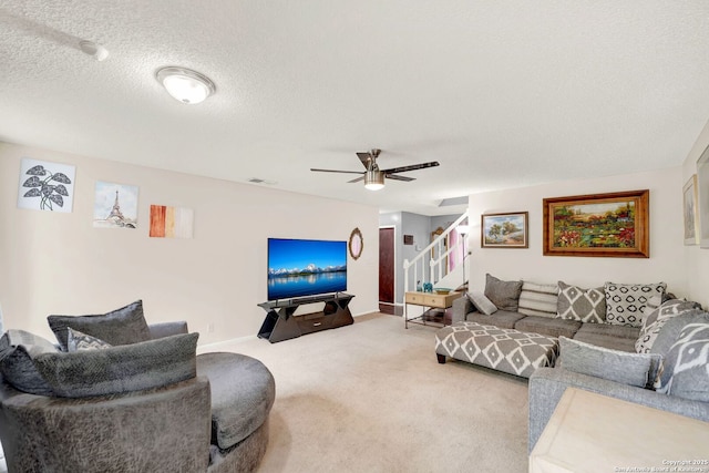 carpeted living area featuring ceiling fan, a textured ceiling, stairs, baseboards, and visible vents