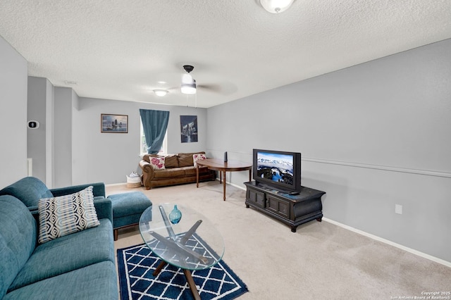 carpeted living area featuring baseboards, a textured ceiling, and ceiling fan